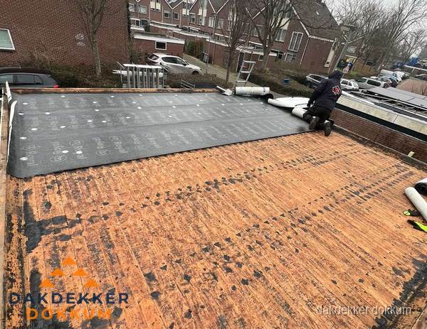 Dakdekker legt onderlaag op plat dak met houten constructie in Dokkum
