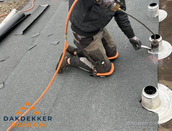 Dakdekker repareert bitumen dakleer bij dakdoorvoer in Dokkum