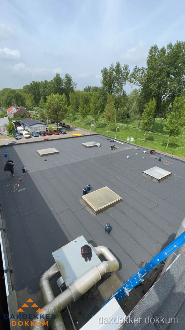 Dakdekker aan het werk op groot plat dak met bitumen in Dokkum