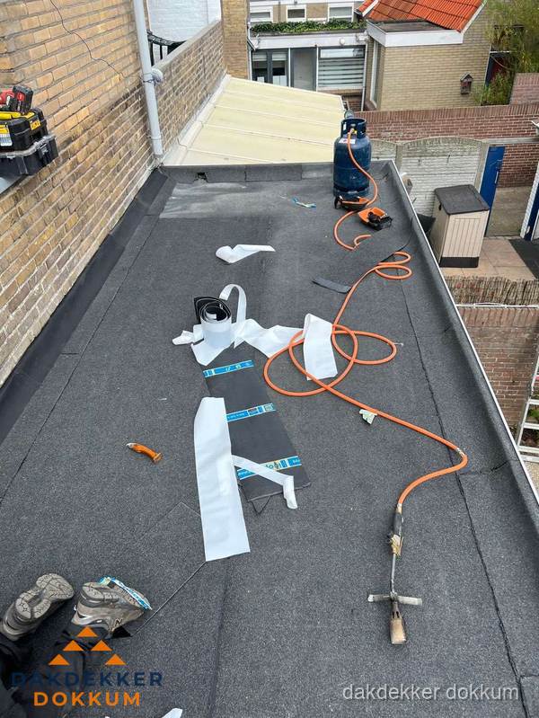 Dakdekkers bezig met bitumen dakbedekking in Dokkum
