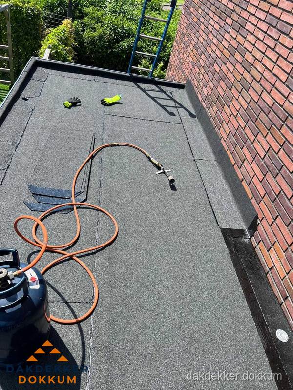 Plat dak met bitumen en brandgereedschap van dakdekkersbedrijf in Dokkum