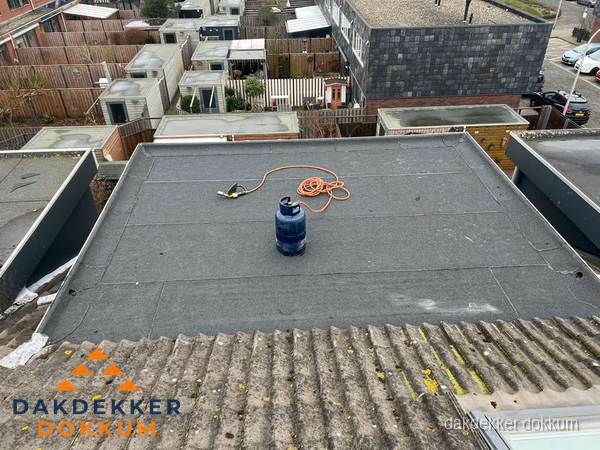 Plat dak met nieuwe bitumen dakbedekking en brandgereedschap in Dokkum