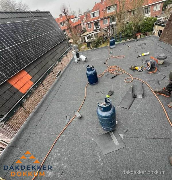 Daklekkage repareren met brandgereedschap op plat dak in Dokkum