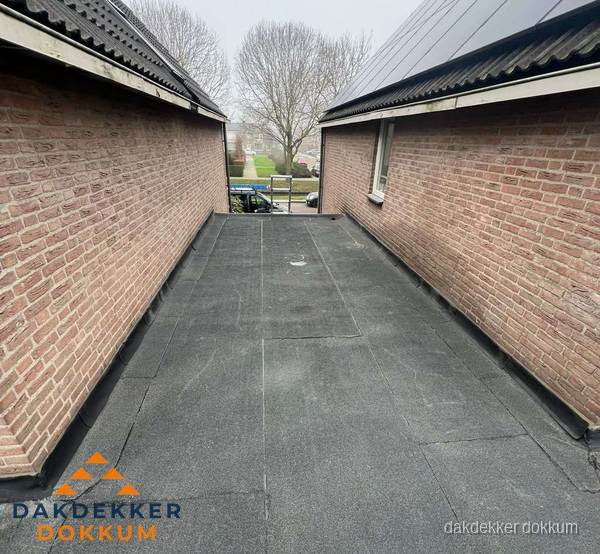 Plat dak met bitumen dakbedekking tussen bakstenen muren in Dokkum