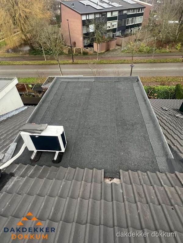 Plat dak inspectie met bitumen bedekking naast schuin pannendak in Dokkum