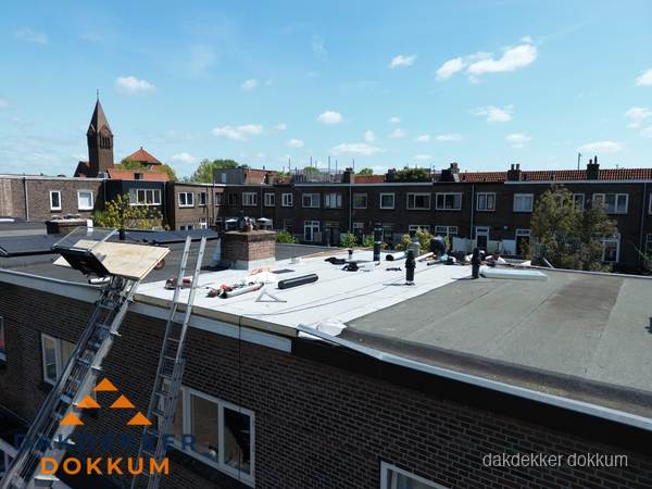 Dakdekkers aan het werk op plat dak in Dokkum